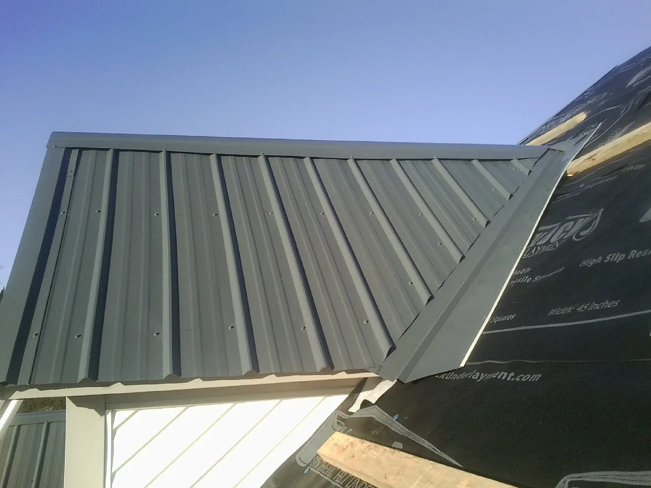 Gray metal roof panels going on over a garage gable in Rye