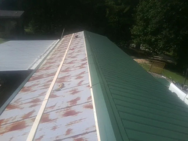 Old rusted panels beside newly installed green metal roofing — Wind Damage Roof Repair by Roofing Brothers in Rye