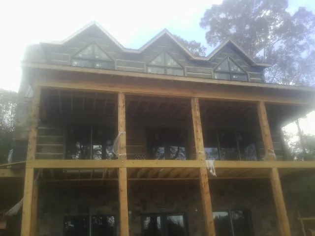Dormers and porch framing on a large log home under construction — Roof Coating work by our crew in Rye