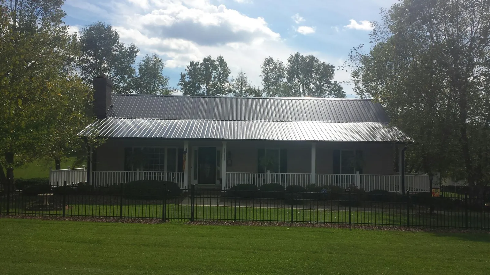 Gray metal roof on a brick ranch with a full width front porch — Gutter Guard Installation work by our crew in Rye